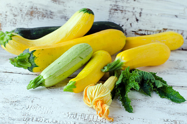 Verschillende courgettes en courgettebloemen op houten tafel